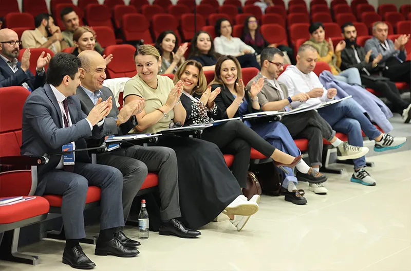 Rem Darbinyan seated with a jury panel in an auditorium, applauding a pitch